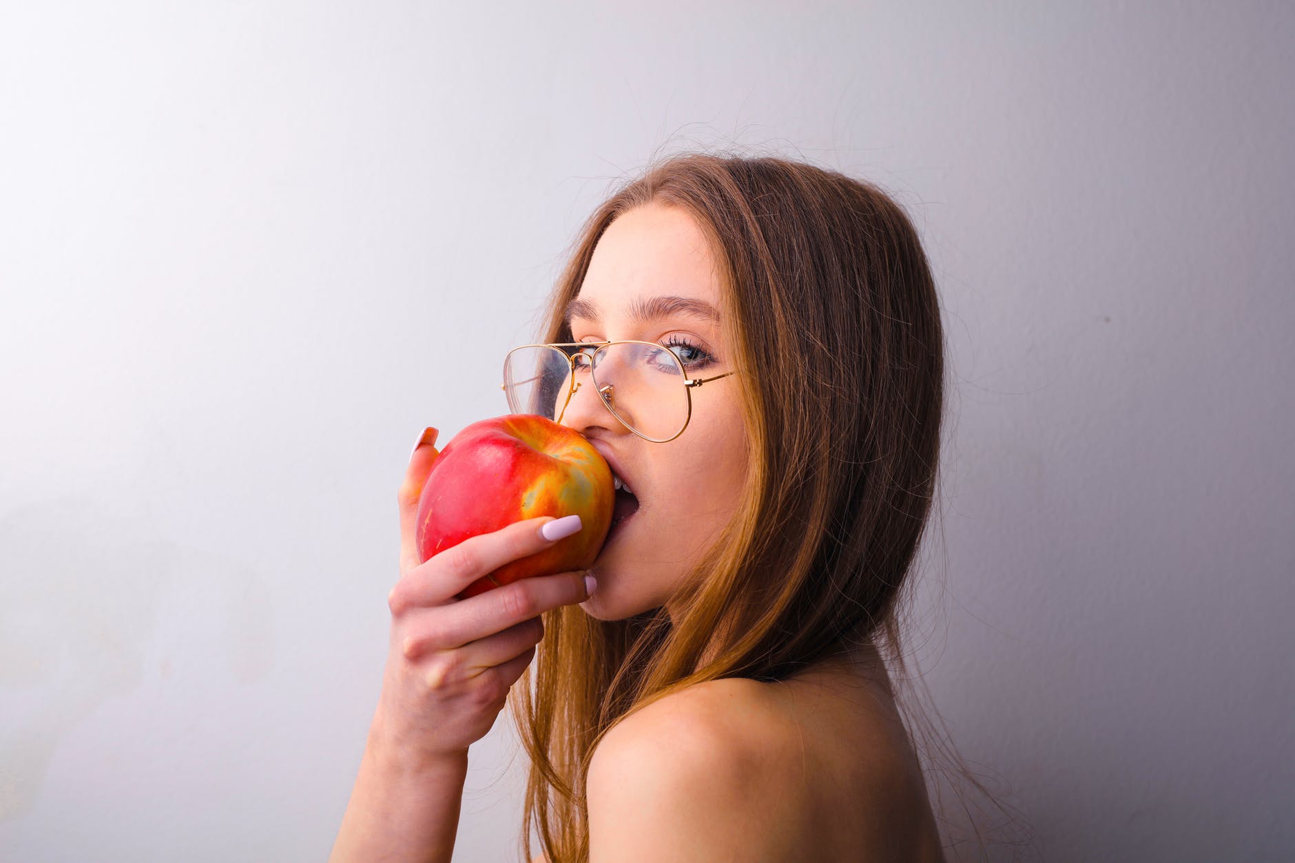 side view photo of woman biting into an apple